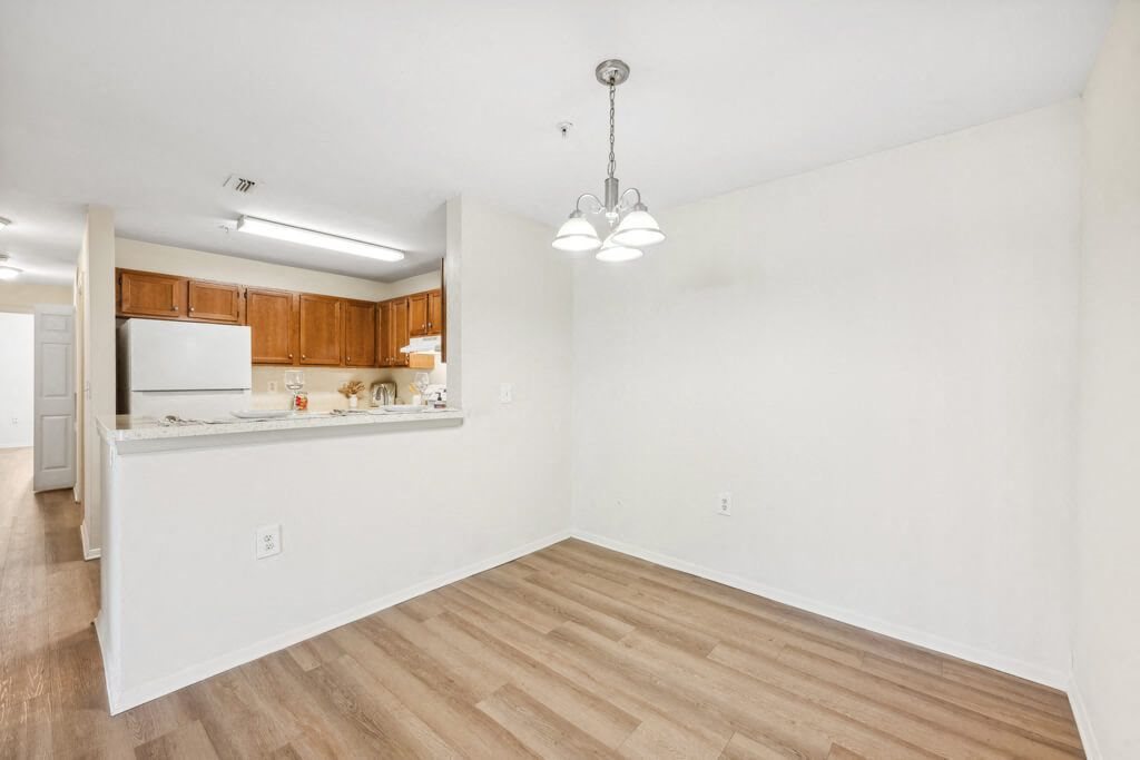 an empty living room and kitchen with wood flooring
